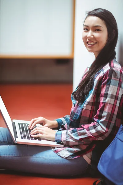 Lachende student zittend op de vloer en met behulp van laptop — Stockfoto