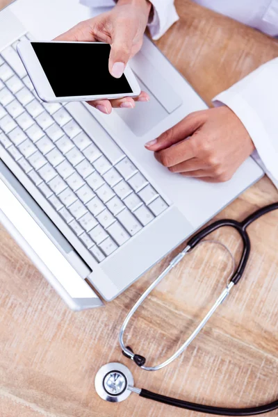 Médecin utilisant smartphone sur bureau en bois — Photo