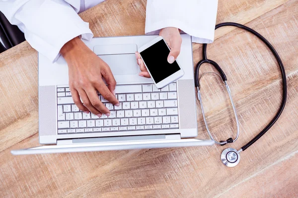 Doctor using smartphone on wooden desk — Stock Photo, Image