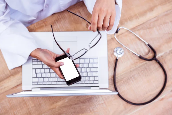 Doctor using smartphone on wooden desk — Stock Photo, Image