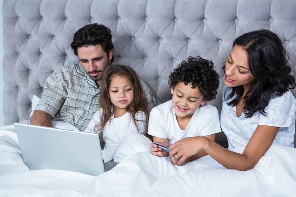 Familia feliz en la cama de compras en línea —  Fotos de Stock