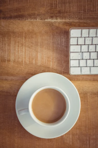 Рабочий стол с кофейной чашкой и клавиатурой — стоковое фото