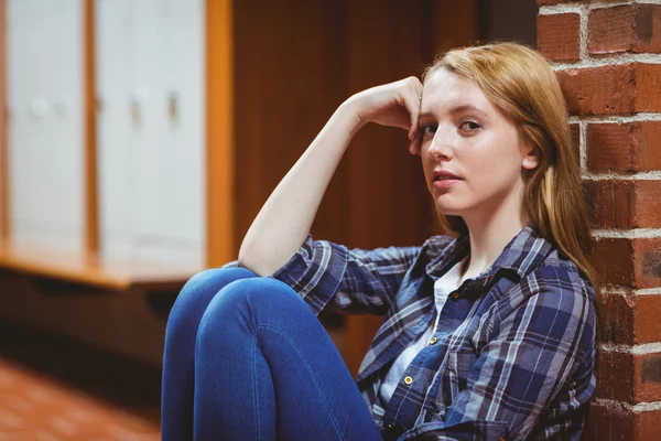 Thoughtful student sitting on the floor against the wall and loo — Stock Photo, Image