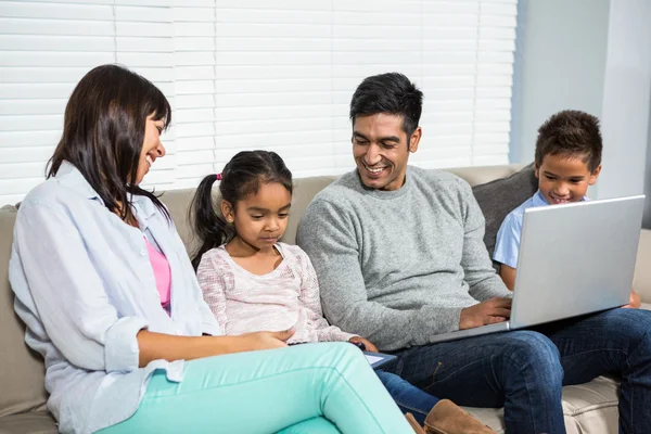 Família sorridente no sofá usando a tecnologia — Fotografia de Stock