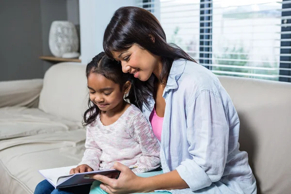Jovem mãe feliz lendo um livro com sua filha — Fotografia de Stock