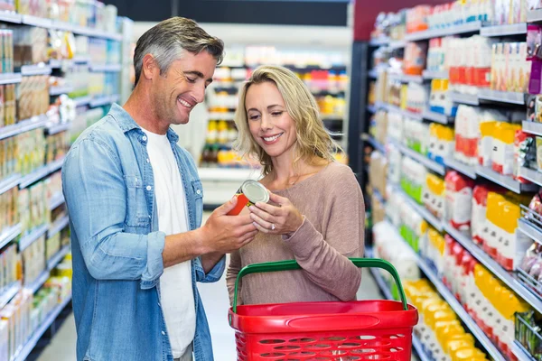 Pareja sonriente sosteniendo comida enlatada — Foto de Stock