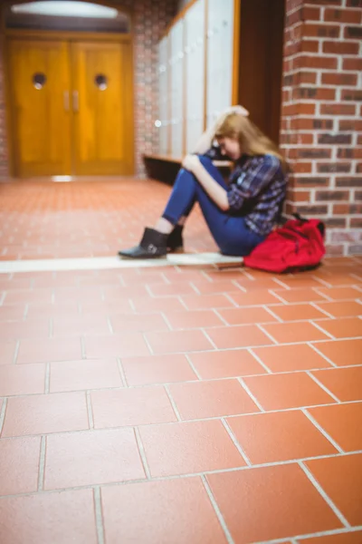 Przemyślane student siedząc na podłodze pod ścianą — Zdjęcie stockowe