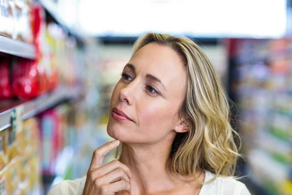 Doordachte vrouw kijken naar planken — Stockfoto