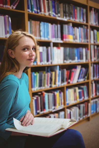 Estudante bonito sentado na cadeira segurando livro — Fotografia de Stock