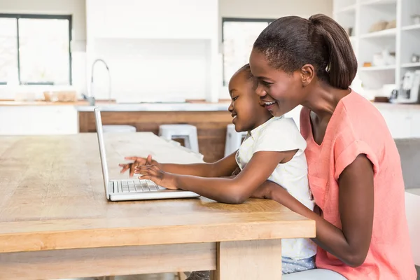 Söt dotter använder laptop vid skrivbordet med mamma — Stockfoto