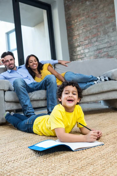 Famiglia sorridente in salotto con disegno figlio — Foto Stock