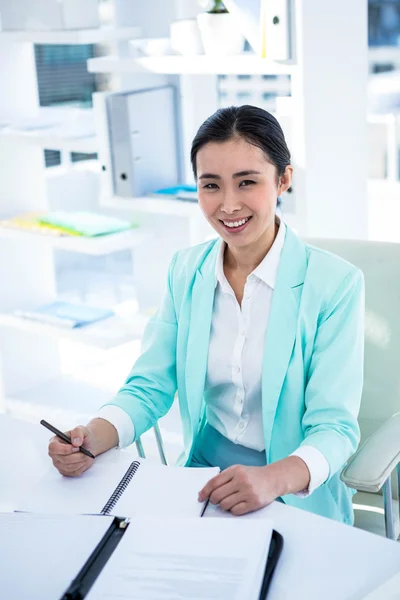 Mulher de negócios sorridente escrevendo em um bloco de notas — Fotografia de Stock