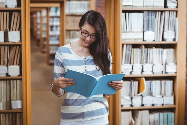 Красивая студентка читает книгу в библиотеке — стоковое фото
