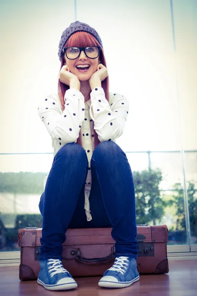 Uśmiechnięty hipster kobieta siedzi na walizkę — Zdjęcie stockowe