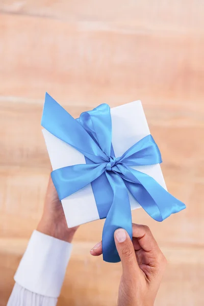 Женщина представляет подарок с голубой лентой — стоковое фото