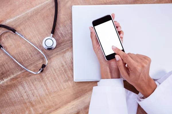 Doctor usando smartphone en escritorio de madera —  Fotos de Stock