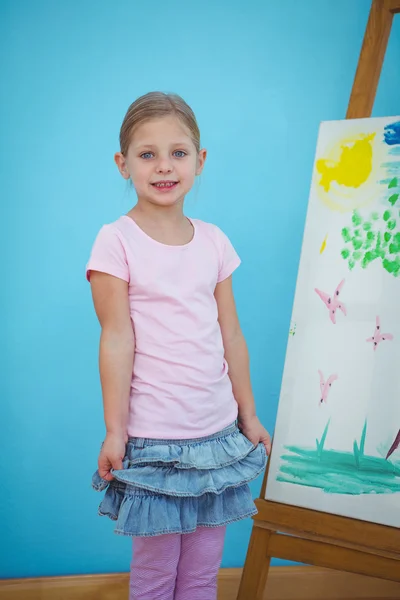 Menina sorridente ao lado de sua pintura — Fotografia de Stock