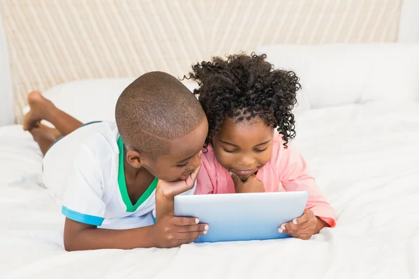 Happy siblings using tablet on bed — Stock Photo, Image