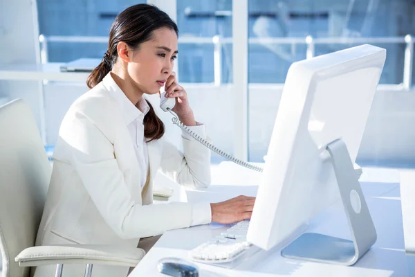 Empresária sorridente usando computador e telefone — Fotografia de Stock