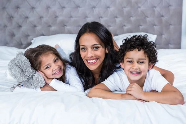 Lachende moeder met kinderen op het bed — Stockfoto