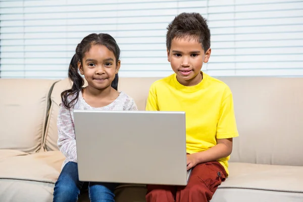 Jovens irmãos sorridentes usando laptop — Fotografia de Stock