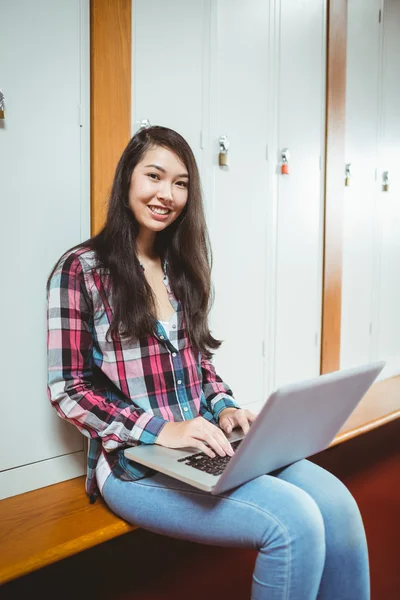 Улыбающийся студент сидит за компьютером — стоковое фото