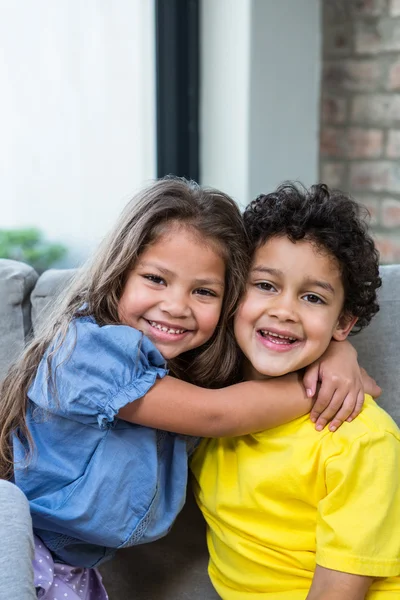Roztomilý sourozenci objímání na pohovce — Stock fotografie