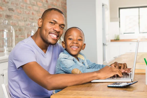 Söta son med laptop på skrivbordet med far — Stockfoto