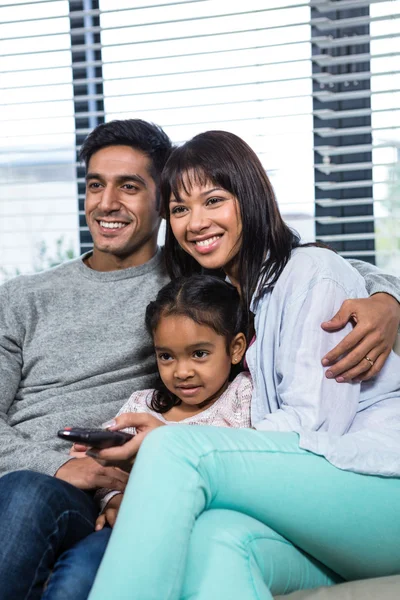 Leende familjen tittar på tv i soffan — Stockfoto