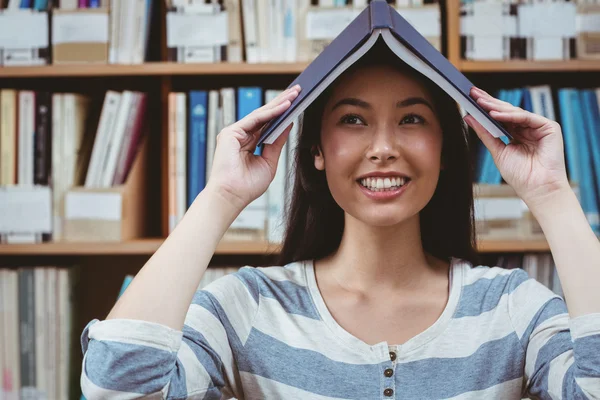 Αστεία φοιτητής που κατέχουν το βιβλίο στο κεφάλι της — Φωτογραφία Αρχείου