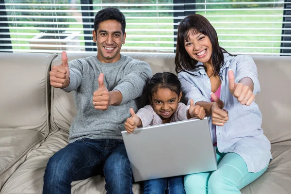 Gelukkige jonge familie met behulp van laptop met duimen omhoog — Stockfoto