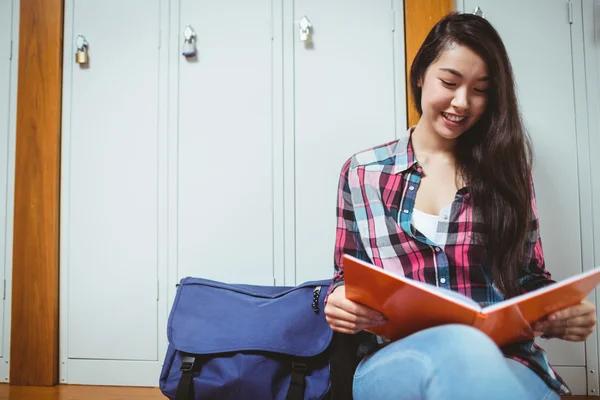 Estudante sorrindo sentado e lendo um caderno — Fotografia de Stock