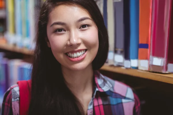 Hymyilevä opiskelija kirjastossa — kuvapankkivalokuva