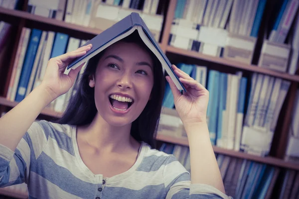 Estudante engraçado segurando livro em sua cabeça — Fotografia de Stock