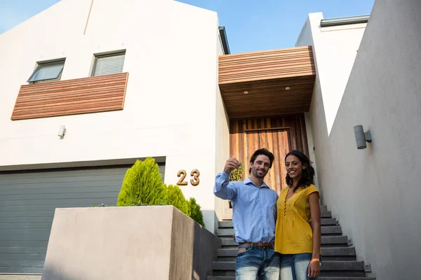 Lyckliga paret framför nya hus visar nycklar — Stockfoto