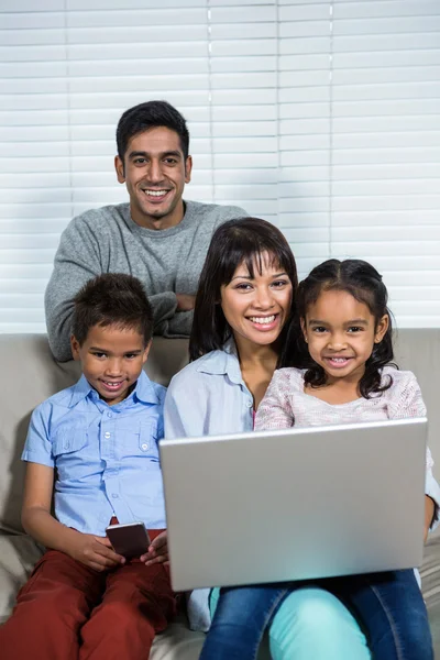 Família sorrindo usando a tecnologia no sofá — Fotografia de Stock