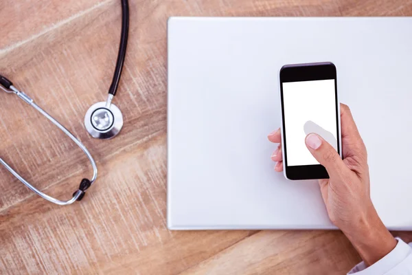 Doctor using smartphone on wooden desk — Stock Photo, Image