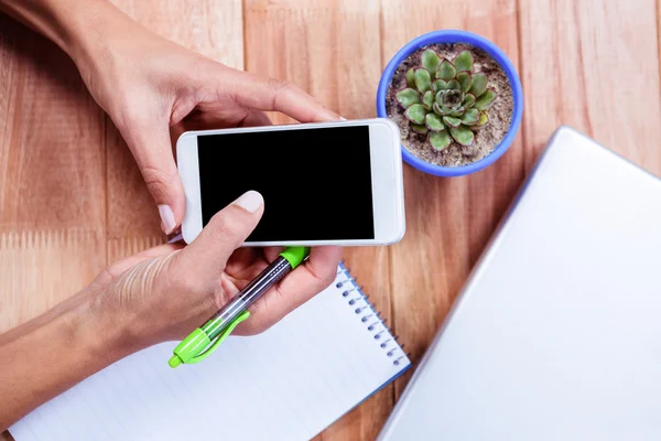 Mãos femininas segurando smartphone e tomando notas — Fotografia de Stock