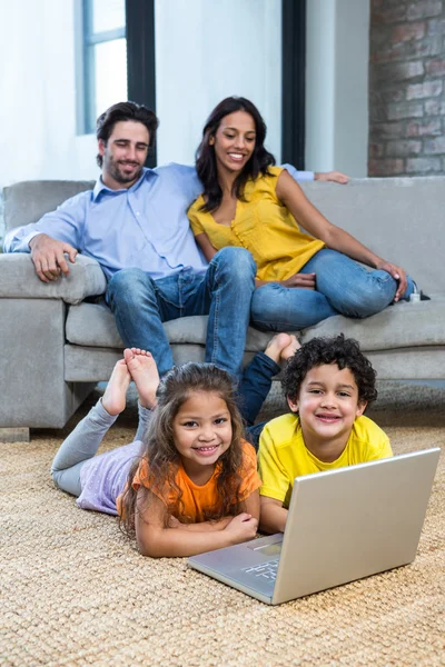 Barn om på mattan i vardagsrummet med laptop — Stockfoto