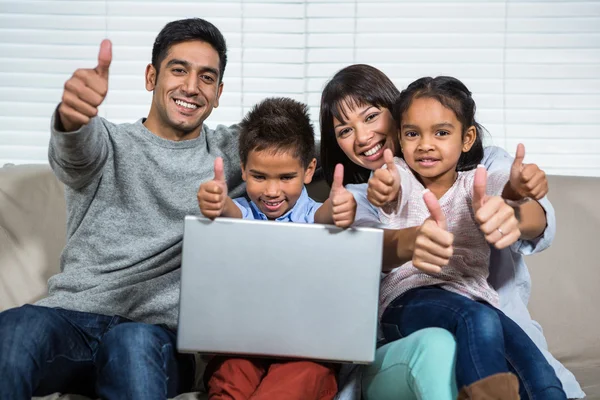 Famiglia sorridente sul divano che mostra i pollici in su — Foto Stock