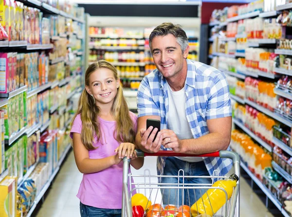Улыбающиеся отец и дочь в супермаркете — стоковое фото