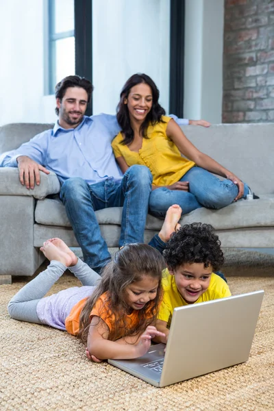 Barn om på mattan i vardagsrummet med laptop — Stockfoto