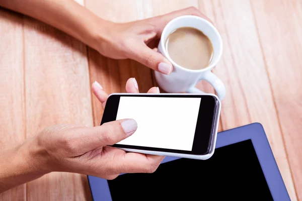 Affärskvinna som håller smartphone och kaffekopp — Stockfoto