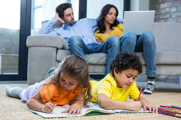 Children laying on the carpet drawing in living room — Stock Photo, Image