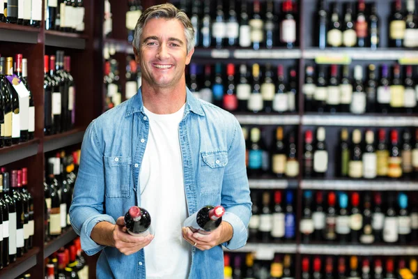 Sonriente hombre sosteniendo botellas de vino — Foto de Stock