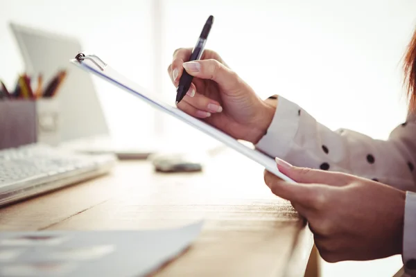 Cropped image of woman writing on clipboard — Stock Photo, Image