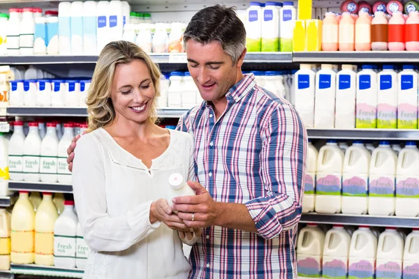 Lachende paar melk kopen — Stockfoto