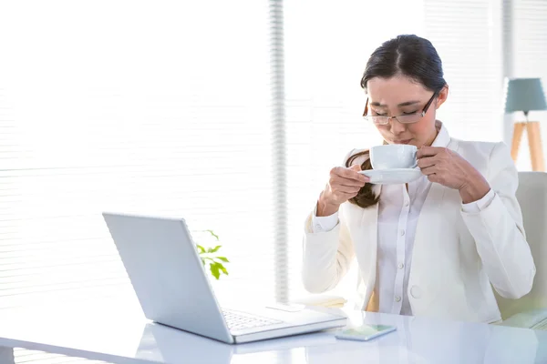 Zakenvrouw drinken koffie achter haar computer — Stockfoto