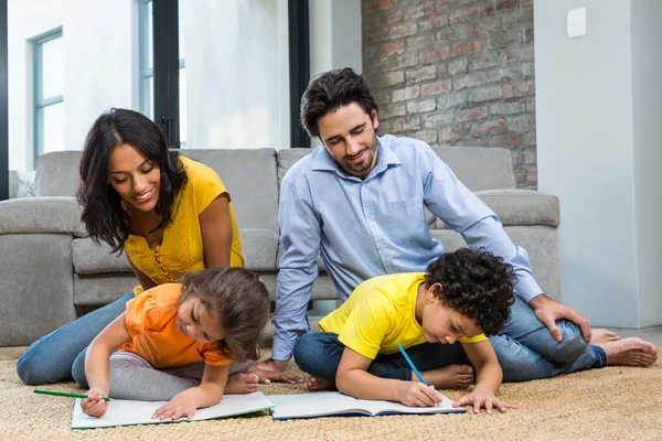 Familjen sitter på mattan i vardagsrummet — Stockfoto