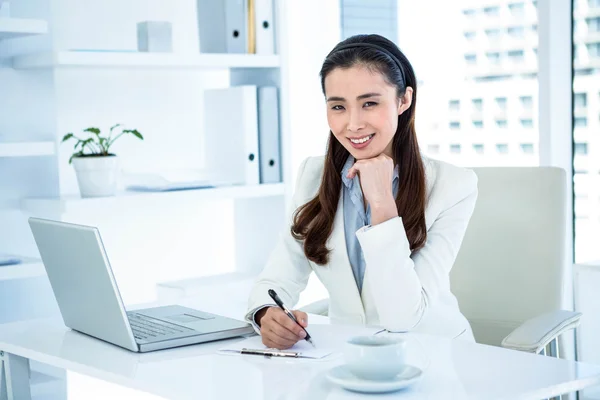 Lächelnde Geschäftsfrau schreibt auf Klemmbrett — Stockfoto